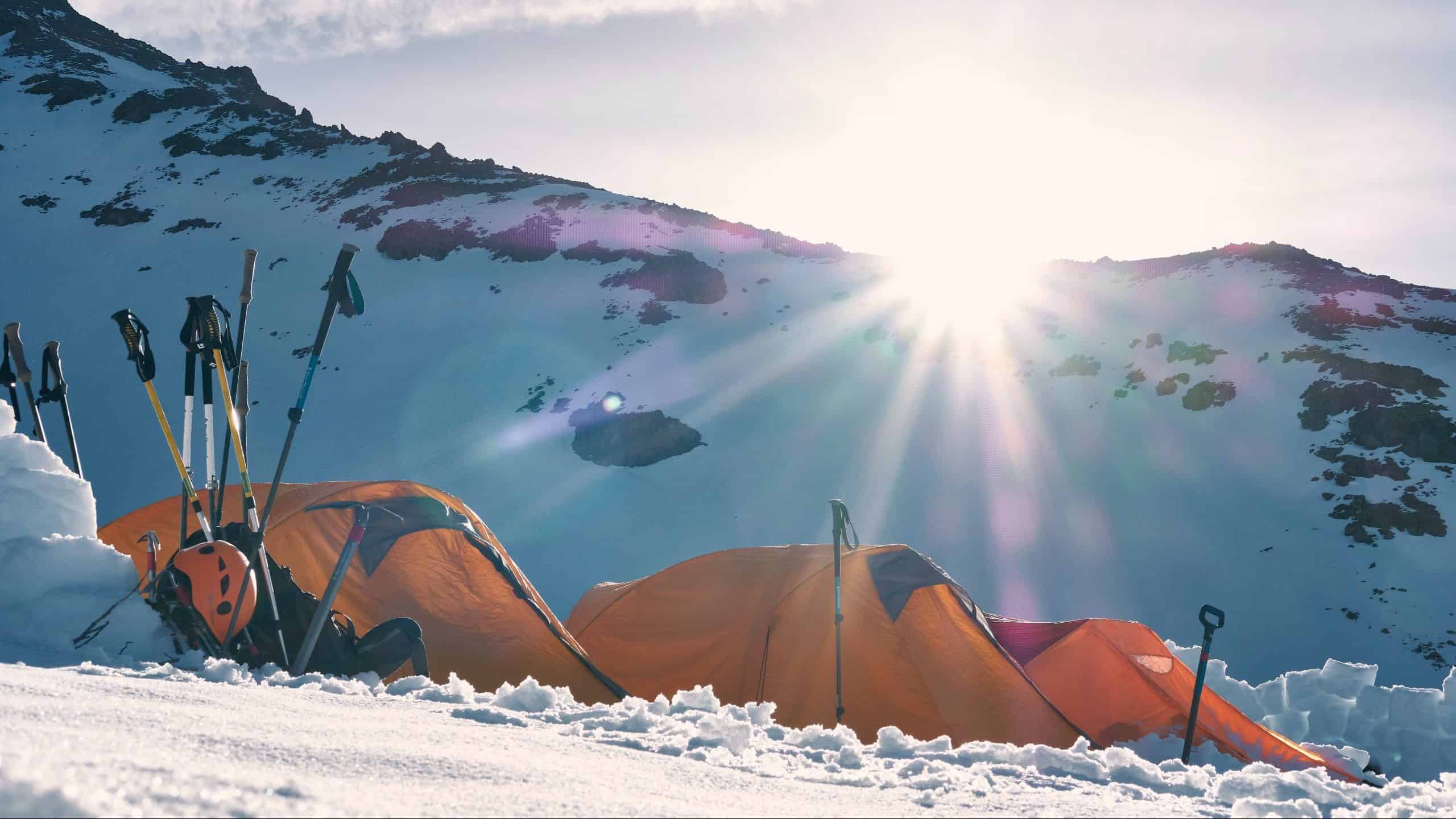 three yellow and red dome tents on snow capped mountain