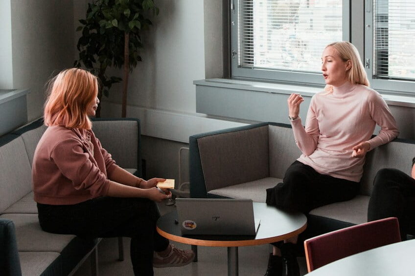 2 women sitting on black sofa