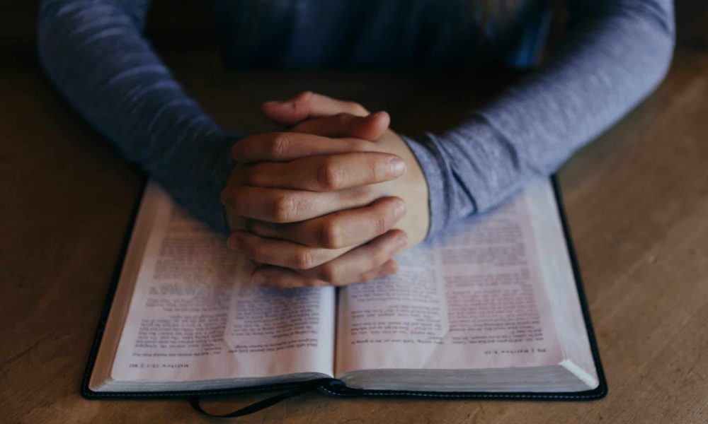 man holding his hands on open book