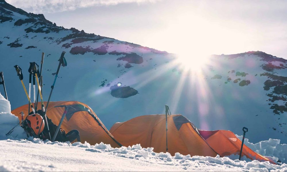 three yellow and red dome tents on snow capped mountain