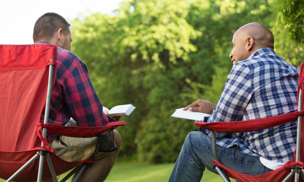 Men having a bible study on a camping trip.